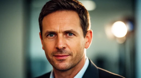 Portrait rapproché d'un jeune enfant de 2 ans avec les mains sur le ventre, dans un environnement de crèche coloré et flou en arrière-plan